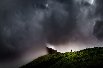 A man walking along a dark and cloudy mountain range in Thailand (Tak province)