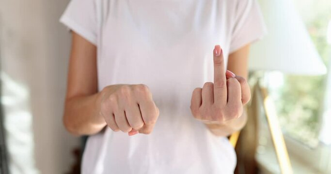 Woman in white t-shirt shows middle finger to camera