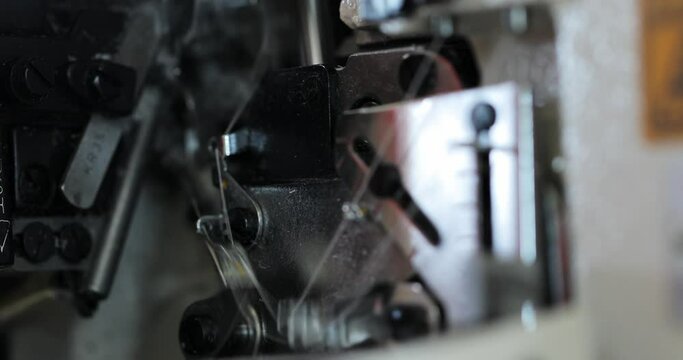 working mechanisms of an overlock sewing machine. macro. in the automatic sewing machine, the thread passes through the knots. needle overlock details in motion