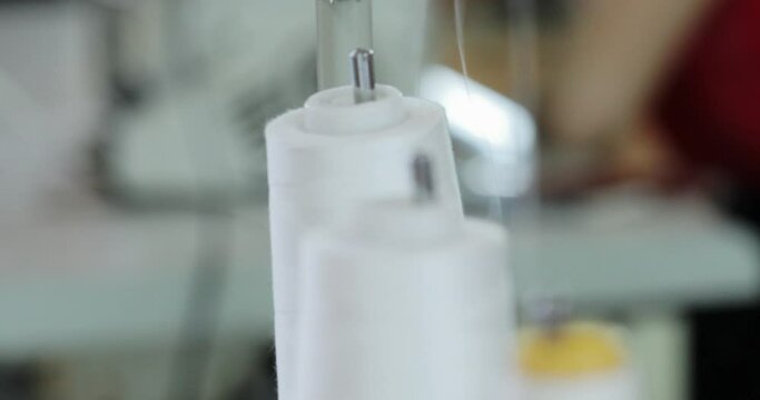 spinning bobbin cores with white thread on a sewing machine. close-up