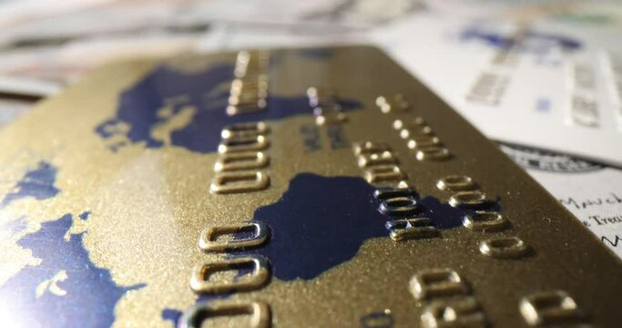 Golden credit card lies on dollar bills pile in studio