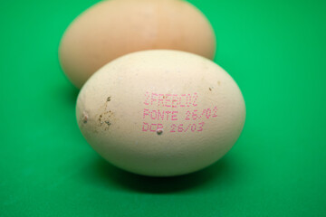 Close-up of Chicken Eggs with Code Stamp on Vibrant Green Background