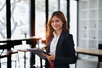 portrait of Beautiful young asian businesswoman presents business profits to colleagues at meeting, explaining business turn over on flipchart to coworkers in office with using tablet