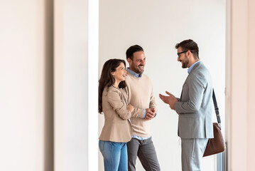 Young married couple talking with a real-estate agent visiting an apartment for sale or for rent. Future parents buying an apartment. Real estate concept. A new beginning - 586090420