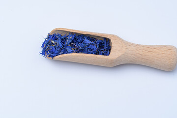 Drewniany nabierak z płatkami niebieskiego bławatka na jasnym tle © Paweł Kacperek