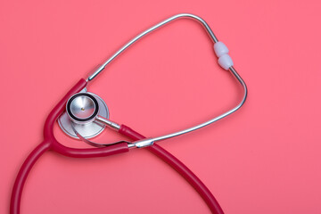 Czerwony stetoskop lekarski na różowym tle - obrazy, fototapety, plakaty