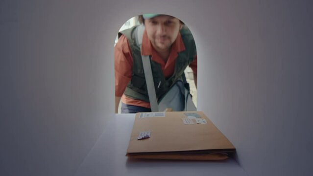 Young postman opening mailbox, placing a couple of letters inside, and then closing while delivering correspondence. POV shot from inside of the mailbox