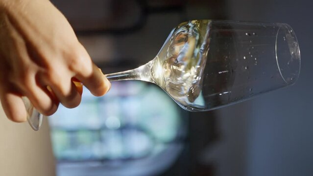 Gold white wine in a glass on defocused dark background . Close up video of wine mixing process inside goblet . Slow Motion . Vertical view.