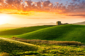 amazing sunset among green spring hills in highland farm with castle , mountains and picturesque colorful sunset on background of landscape