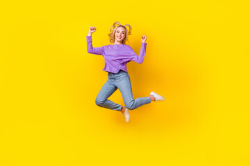 Fototapeta na wymiar Full size photo of pretty young girl jumping raise fists have fun dressed stylish violet clothes isolated on yellow color background