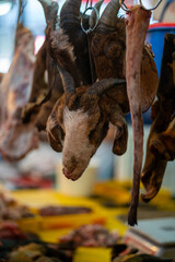 A slaughtered goat head is hanging at a butcher stall in the local market in Malaysia. Selective focus, Vertical Shot. 