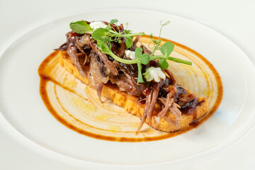 Beef bruschetta on a white porcelain plate on a dark gray table