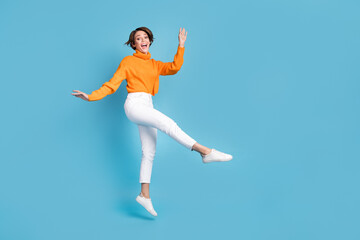 Fototapeta na wymiar Full size photo of pretty young girl graceful dance have fun party jumper wear trendy orange garment isolated on blue color background