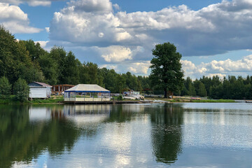summer sunny day on bank of calm lake with gazebo near water edge