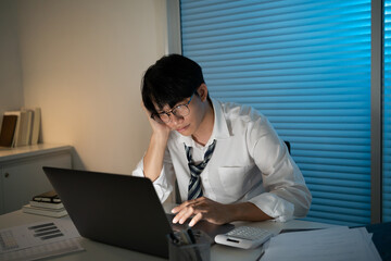 Tired Asian business man falling asleep at table Alone Working holding his head on hands after late night work. asian male employee