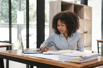 Black business woman calculating finance, money, using calculator, laptop computer at home workplace table, counting budget, paying bills, taxes, rent, mortgage fees