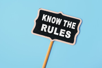 Know the rules - text on a small chalkboard on a blue background. Top view. Business process regulation concept