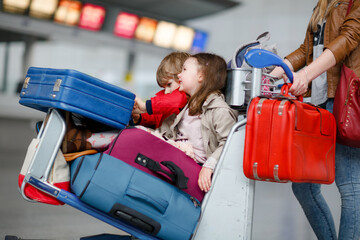 Two little kids, boy and girl, siblings and mother at the airport. Children, family traveling,...