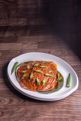 grilled bbq fresh whole seafood stingray fish with spicy samba chilli sauce and lady finger vegetables on banana leaf plate wood table asian halal food menu