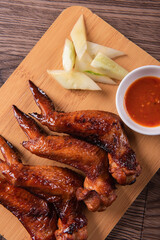 grilled bbq roasted golden honey chicken wing with spicy chilli sauce and onion on wood table asian chinese halal meat banquet snack menu for restaurant and stall