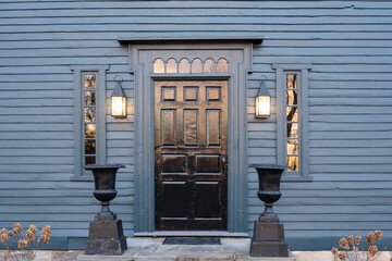 A wooden door on a blue colonial American house with sunset light