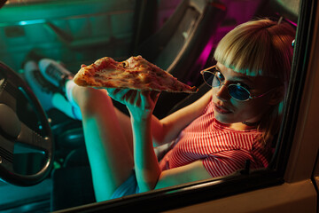 Girl eating pizza in car.
