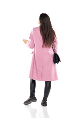 Rear view of a young woman in winter coat, and black boots posing on a white
