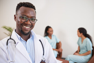 Close up portrait of smiling Black doctor with nurses sitting behind