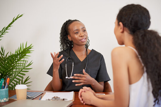 Candid shot of Black female doctor explaining to patient during GP consultation