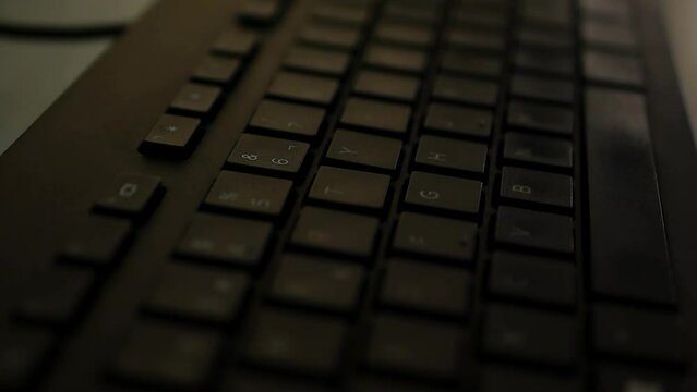 Close up shot of black keyboard and computer inside office - panning shot
