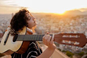 Young brunette woman learns to play classical guitar outdoors