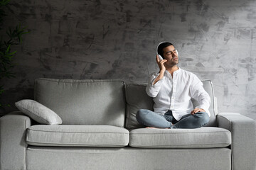Fototapeta na wymiar Hispanic man listening to music on sofa