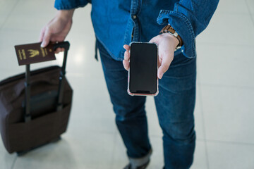 Top view hand man passenger showing passport issue and e-ticket to flight. Touris man showing passport and boarding pass on mobile phone. Businessman showing smartphone online air ticket at airport.