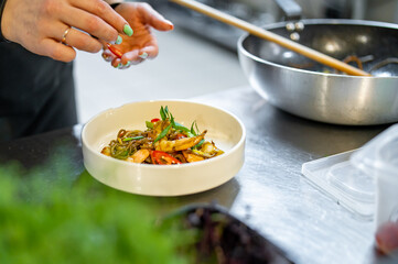 Chef cooking Stir fry noodles with vegetables and shrimps on restaurant kitchen