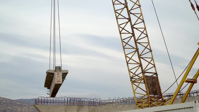 Roundabout and traffic bridge construction site with a crane lifting up a big concrete bridge segment