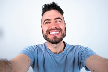 Photo of Young caucasian man wearing blue T-shirt over white background do selfie