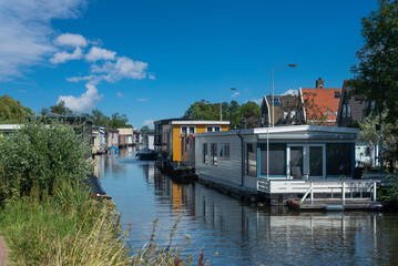 Fototapeta na wymiar Hausboote auf dem Kanal Braakslot in Zaandam Ortsteil Kalf. Provinz Nordholland in den Niederlanden