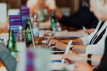 Close up photo of an elderly woman typing on a laptop at a seminar