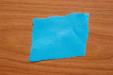 Ripped blue paper piece with edges on a isolated wooden background