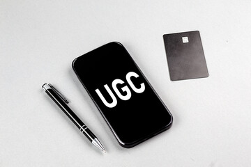 UGC word on smartphone with credit card and pen