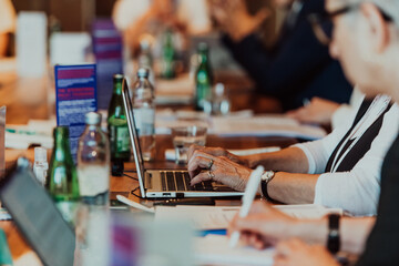 Close up photo of an elderly woman typing on a laptop at a seminar