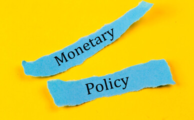 MONETARY POLICY text on a blue pieces of paper on yellow background, business concept