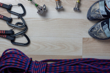 climbing rope, shoes, some carabiners and cams on wooden background with empty space