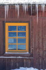 window of a wooden hut with icicles hanging above it