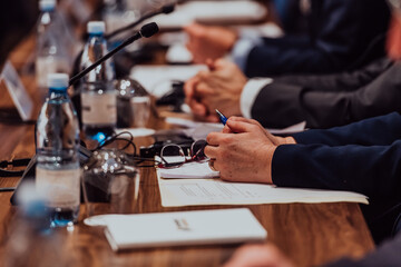 Closeup shot of business people hands using pen while taking notes on education training during business seminar at modern conference room