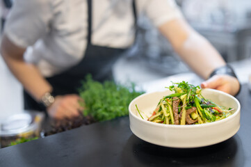 chef hand cooking Roast beef salad with vegetables on restaurant kitchen