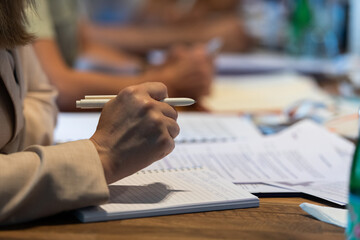 Closeup shot of business people hands using pen while taking notes on education training during business seminar at modern conference room