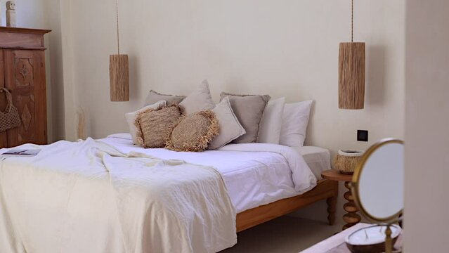 Entering bohemian designed bedroom villa through the doorway revealing aesthetic wooden furniture and king size bed with lots of pillows