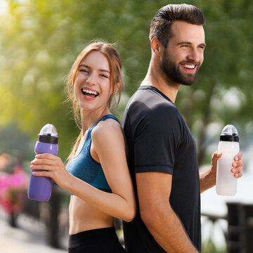 Square image of happy smiling, excited couple holding plastic water bottles, woman with man or bearded coach trainer, after successful training, outdoors. Fitness, sport, workout concept.