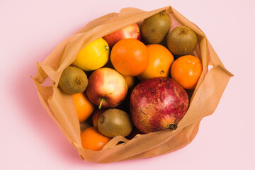 Fruits in a reusable bag on a pink background. Earth day and zero waste concept.